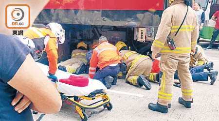 消防員搶救被困車底婦人。（讀者提供）