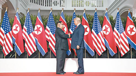 金正恩（左）與特朗普（右）「世紀握手」十二秒，笑臉相對。（美聯社圖片）