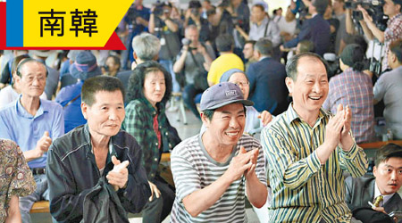 首爾民眾看到特金兩人「世紀握手」，都拍掌歡笑。（美聯社圖片）