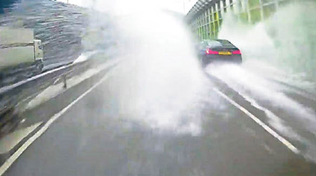 有私家車在大雨下輾過水氹，意外濺起大量水花，鄰線的電單車慘中招。（互聯網圖片）