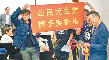 聯會代表手持「公民民主黨，攜手賣香港」橫額示威，狙擊正在訪美嘅楊岳橋（右一）。（互聯網圖片）