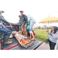 菲律賓救援人員在泥濘中掘出遺體。