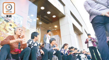 大批內地旅客蹲坐在東涌商店前梯級休息及進食。（黃偉邦攝）