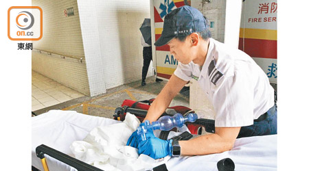 救護員為男嬰戴上氧氣罩送院搶救。（郭垂垂攝）