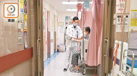 伊院<br>伊院病房擠迫，醫護人員在走廊照顧病人。