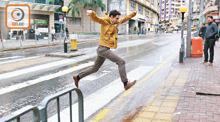 途人飛躍水浸路面一剎。（張開裕攝）