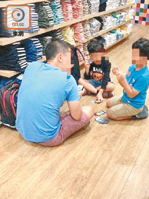 銅鑼灣一間連鎖時裝店內，有父子坐在地上玩紙牌遊戲。（互聯網圖片）