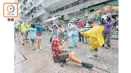 有小朋友聯群結隊，以水槍向一旁的路人「發動攻勢」。（陳章存攝）