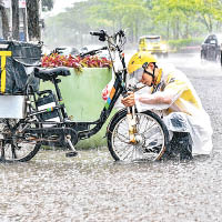 外賣配送員在大雨中修理電動車。（中新社圖片）