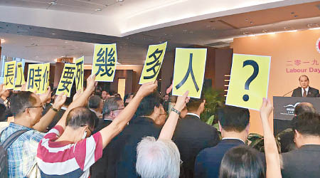 張建宗於勞動節酒會致詞期間遭示威者舉標語抗議。（互聯網圖片）
