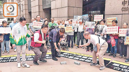 請願人士用鐵錘砸碎磚頭，希望該局可收購該處重建。（受訪者提供）