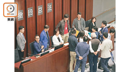 民主派議員於會議開始前包圍主席台，並在主席台後方貼上「撤回惡法」標語。（袁志豪攝）