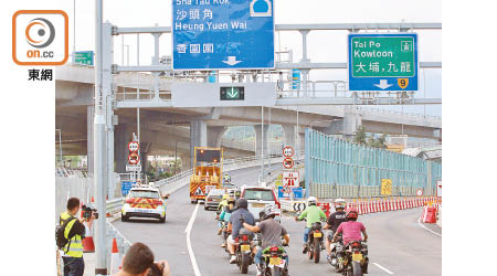 昨早八時，多輛電單車、私家車、貨車，在警車及工程車帶路下駛入新路。（吳建明攝）