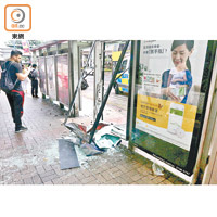 巴士站廣告燈箱被撞毀，玻璃碎片散落地上。
