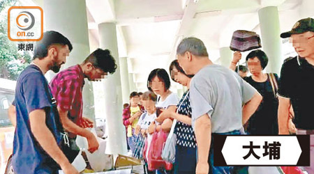 平日下午，港鐵大埔墟站外兩名南亞小販推着杧果叫賣，吸引不少人購買。