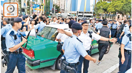 與示威者發生衝突的市民由警員護送乘的士離開。