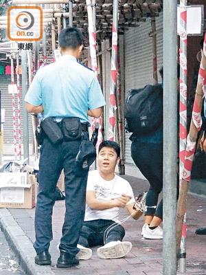 男子坐在地上，向警員講述案發的經過。（胡德威攝）