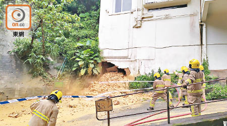 洋房底部露出大窿，消防員射水沖開泥土。（吳建明攝）