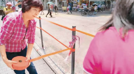 蔣麗芸拎起成卷顏色帶綁欄杆，等市民容易辨認馬路邊。（互聯網圖片）