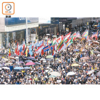 民主派昨發起非法遊行，大批市民參加，沿途高舉多國國旗。（何天成攝）