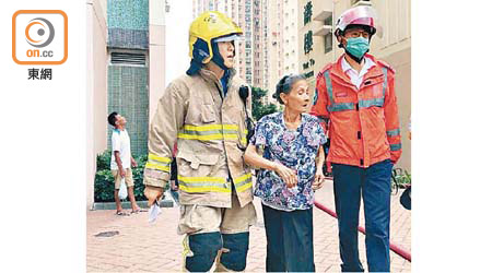 起火單位婦人由救援人員攙扶。（梁志雄攝）