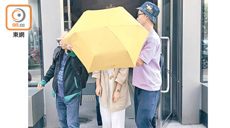 女被告陳子晴（中）在雨傘遮擋下離開法院。