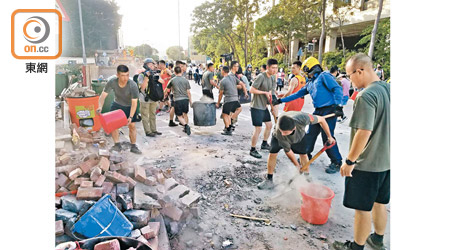 解放軍分工合作清理堵路的磚頭雜物。（余宏基攝）