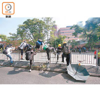 大批示威者爬過馬路中心鐵欄逃走。