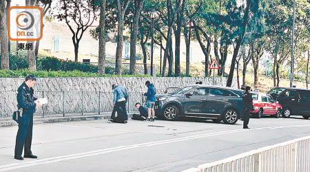 賊車及警方車輛停在現場，兩名疑犯坐在路邊。