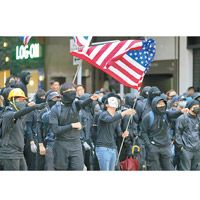 大批參加遊行的黑衣示威者揮舞美國國旗。（美聯社圖片）