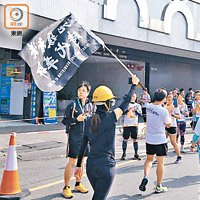 有跑手揮動「光復香港，時代革命」旗幟。（李浮南攝）