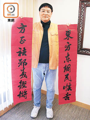 王國興揮毫寫出「東方東網民喉舌，方正祛邪義鏗鏘」對聯，剛勁有力。（溫國佳攝）