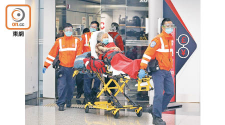 一名老婦昨在機場由救護員送院。（李志湧攝）