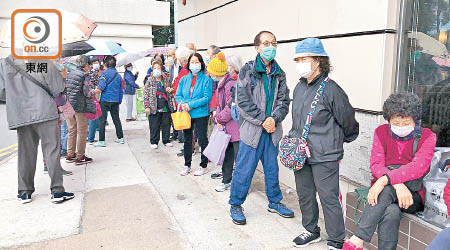 市民冒雨排隊輪候派口罩。（任方攝）