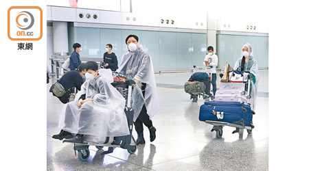 飛機是播毒熱點，部分旅客穿上保護衣以免受感染。（黃偉邦攝）