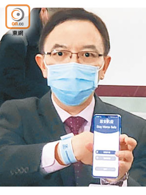 政府資訊科技總監林偉喬展示家居檢疫需佩戴的電子手環及手機App。