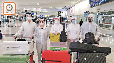 鍾欣潼（左二）及蔡卓妍（中）與一眾藝人身穿保護衣步出機場。（文健雄攝）
