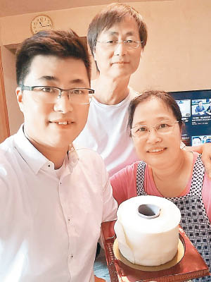 顏汶羽（左）拎住個廁紙蛋糕同媽媽（右）、爸爸（中）合照。