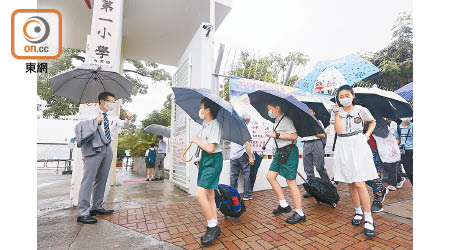 復課日遇上黃雨，撐着雨傘的學生都顯得有點狼狽。（何天成攝）