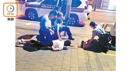 警員將兩名男子撳在地上。
