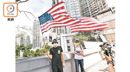 有參與遊行者展示美國國旗。（黃偉邦攝）
