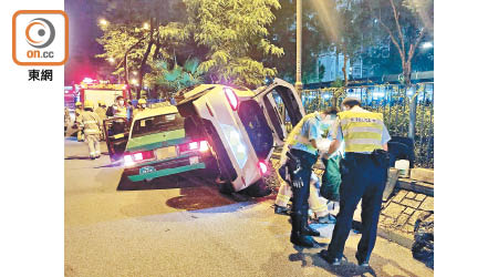 私家車剷上石壆翻側壓的士，警員在意外現場調查。（楊日權攝）