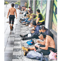 地盤工人在炎熱天氣下，一排坐開在街頭開餐。