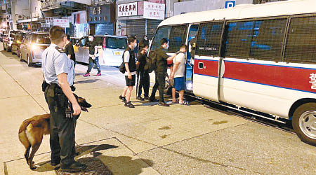 深水埗：警員帶同警犬協助冚賭，被捕人士押上警車。