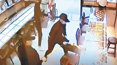 行劫過程連環圖兩名劫匪揮錘扑爆飾櫃，一人持刀指嚇職員。