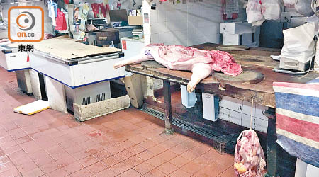 沙田街市清晨時分有工人將豬殼放在肉枱上，內臟則掛在枱邊極貼近老鼠籠。