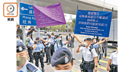 警員在法院外高舉港區國安法的紫色警告旗，同時舉起藍旗。（黃仲民攝）