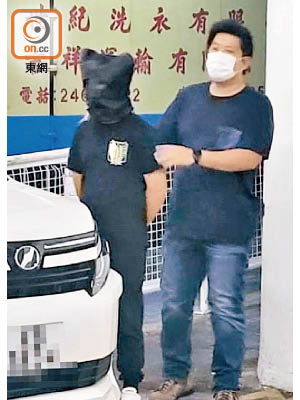 被捕男疑犯（蒙頭者）由警員看管。（余宏基攝）