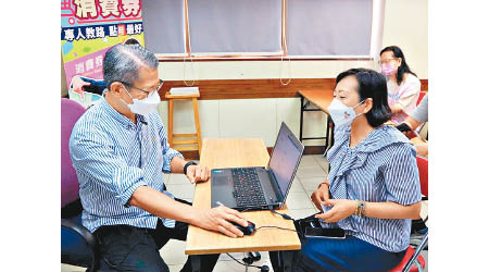 陳茂波（左）為麥美娟進行網上登記手續。