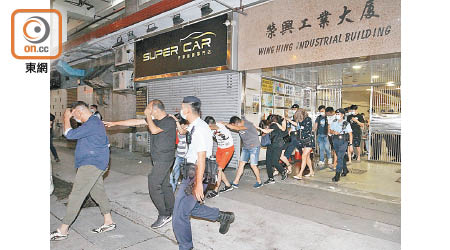 荃灣工廈被捕男女由警員押走。（胡德威攝）